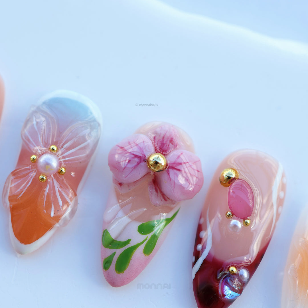 Grace vintage floral press-on nails in close-up, with nude bases, hand-painted flowers, and small gem accents