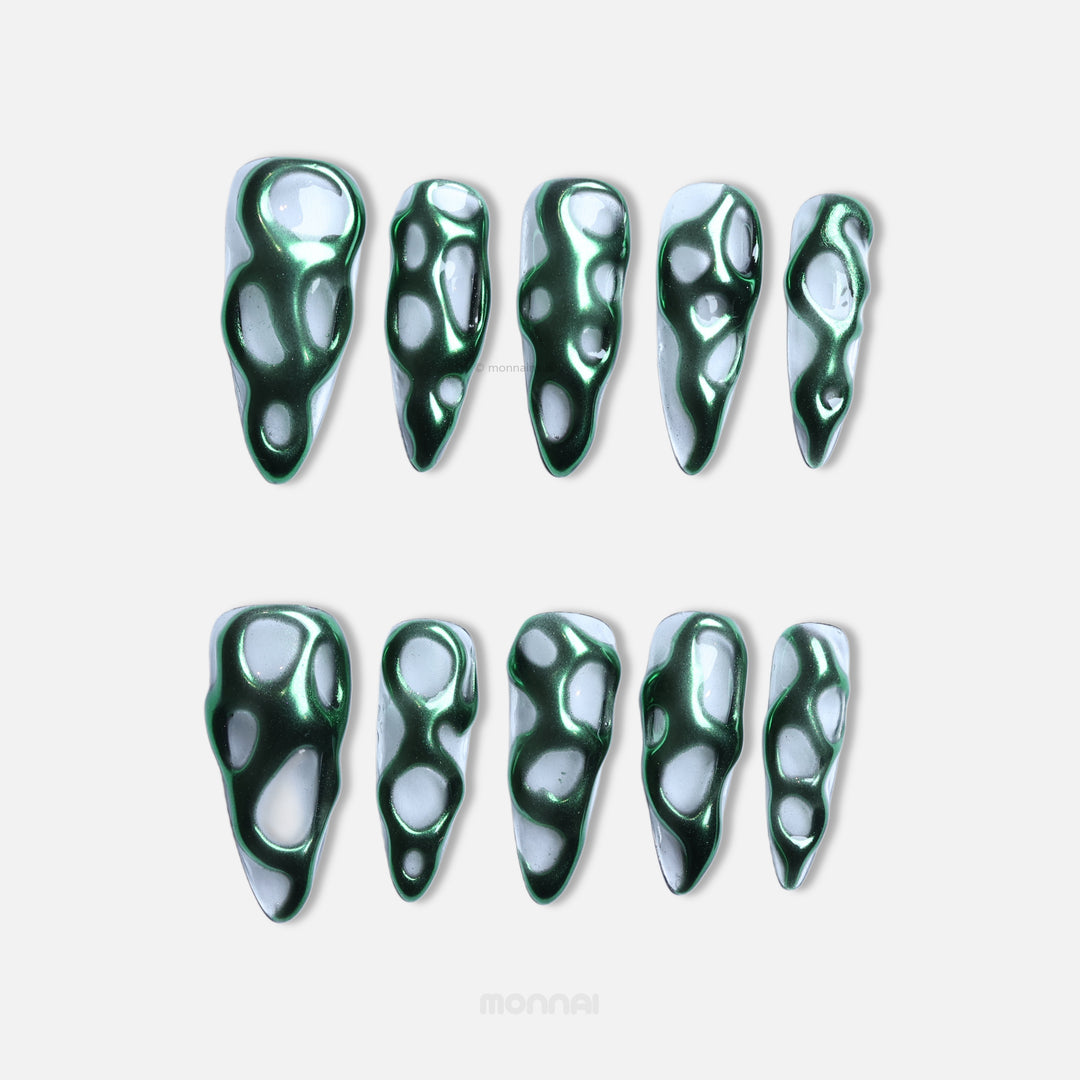 Green Flow press-on nails laid out in a full set, with metallic green chrome flowing over a clear base in an abstract sculptural pattern.