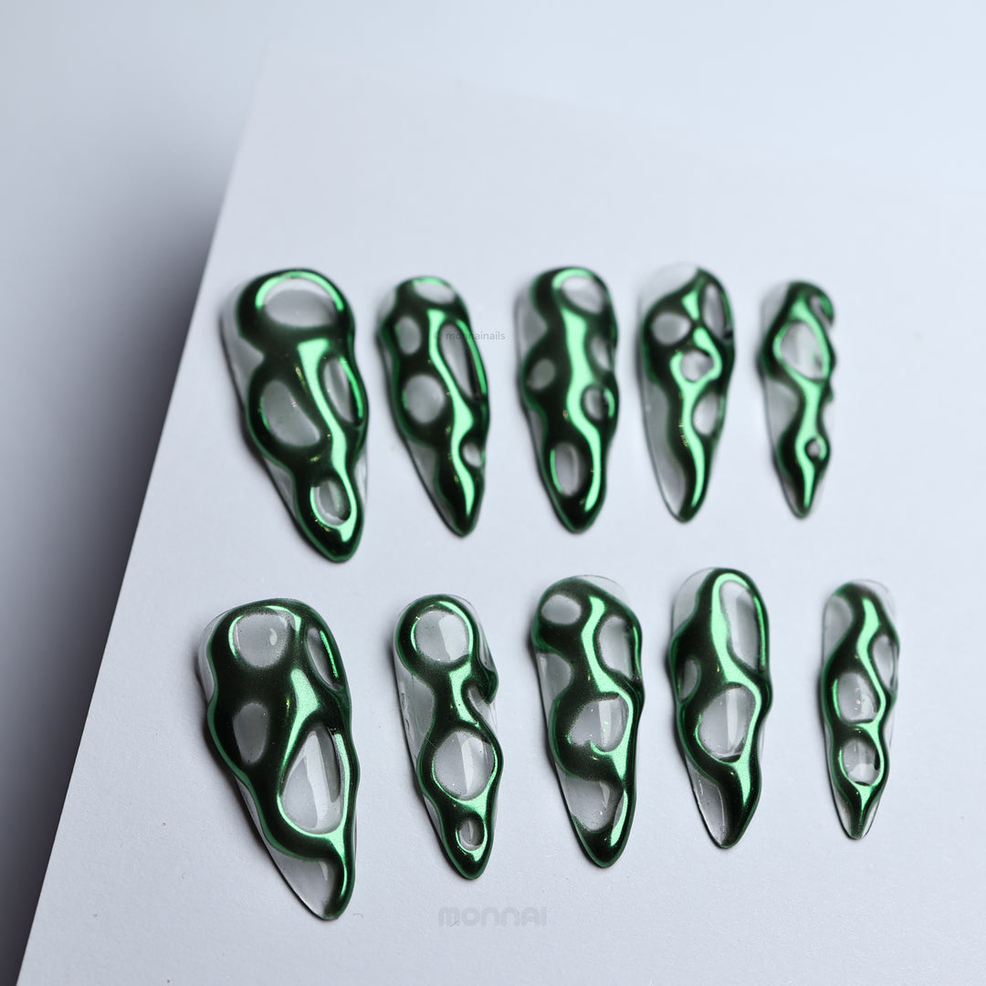 Green Flow press-on nails with metallic green chrome and clear openwork abstract pattern, laid out in a full set.