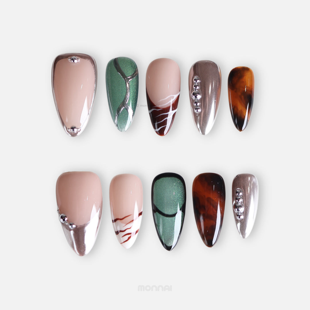 Green Light press-on nails laid out with forest green cat-eye, tortoiseshell, chrome, and marble accents