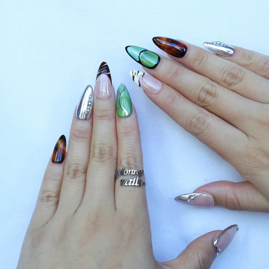 Green Light press-on nails worn on hands, with forest green cat-eye, tortoiseshell, and silver chrome accents.
