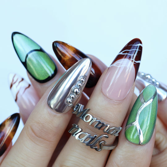 Green Light press-on nails worn on hand with forest green cat-eye, tortoiseshell, and silver chrome accents