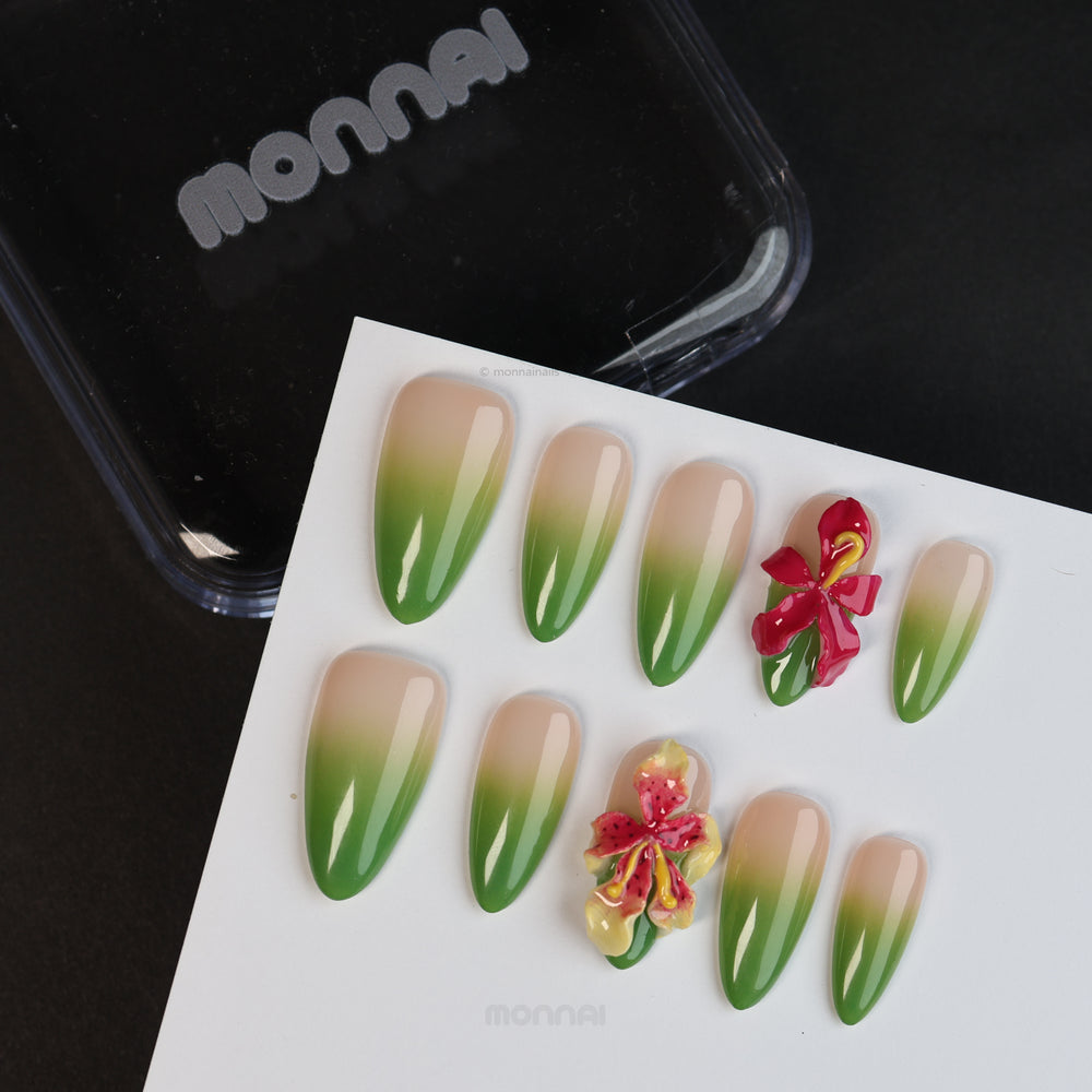 Green Sprout press-on nails laid out close-up, sheer nude with green ombré and 3D orchid details