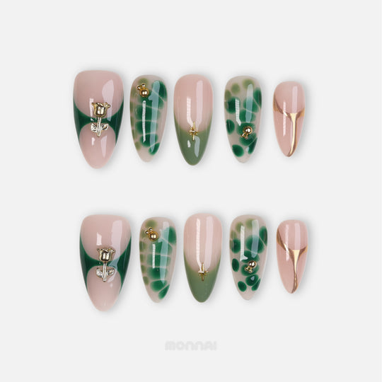 Green Swan press-on nails laid out in two rows, with sheer nude, emerald abstract details, gold lines, and sculpted gold rose accents.