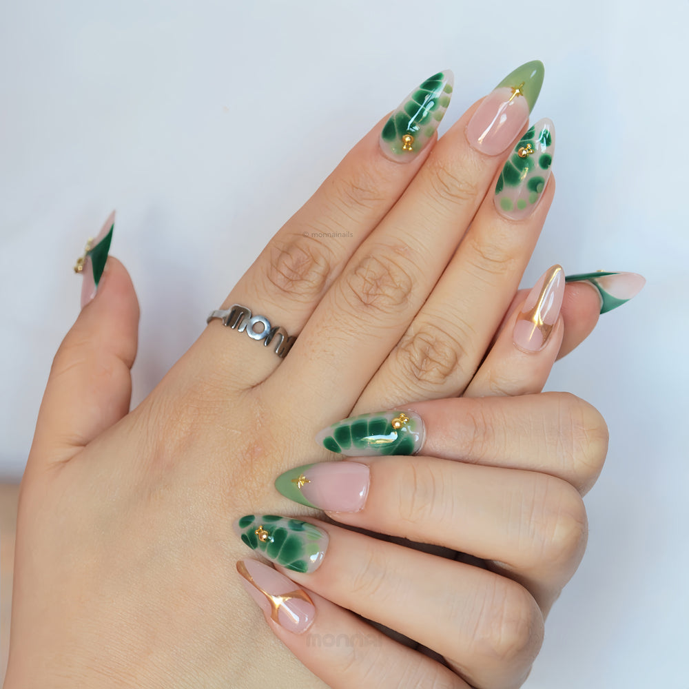 Green Swan press-on nails worn on hands, sheer nude base with emerald green abstract details and fine gold accents.