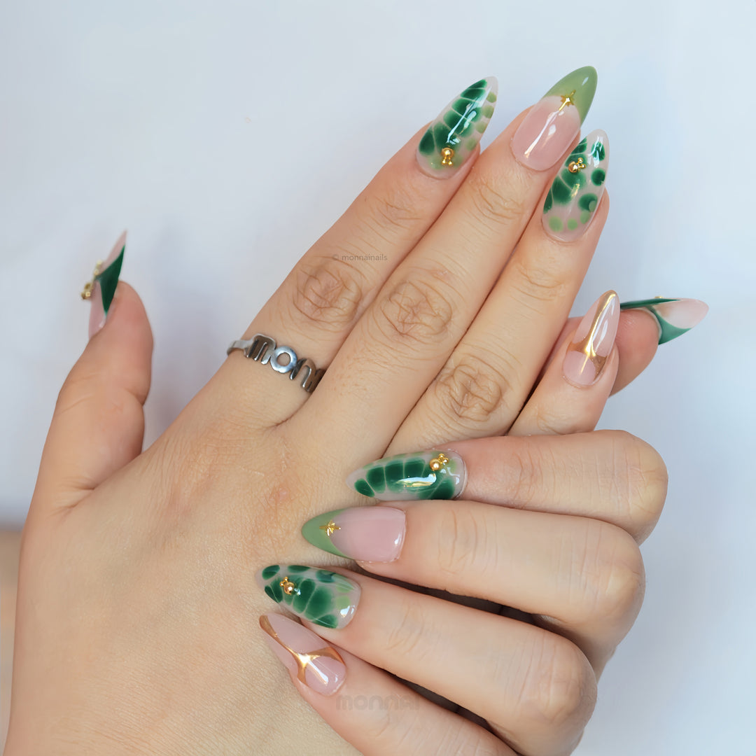Green Swan press-on nails worn on hands, sheer nude base with emerald green abstract details and fine gold accents.