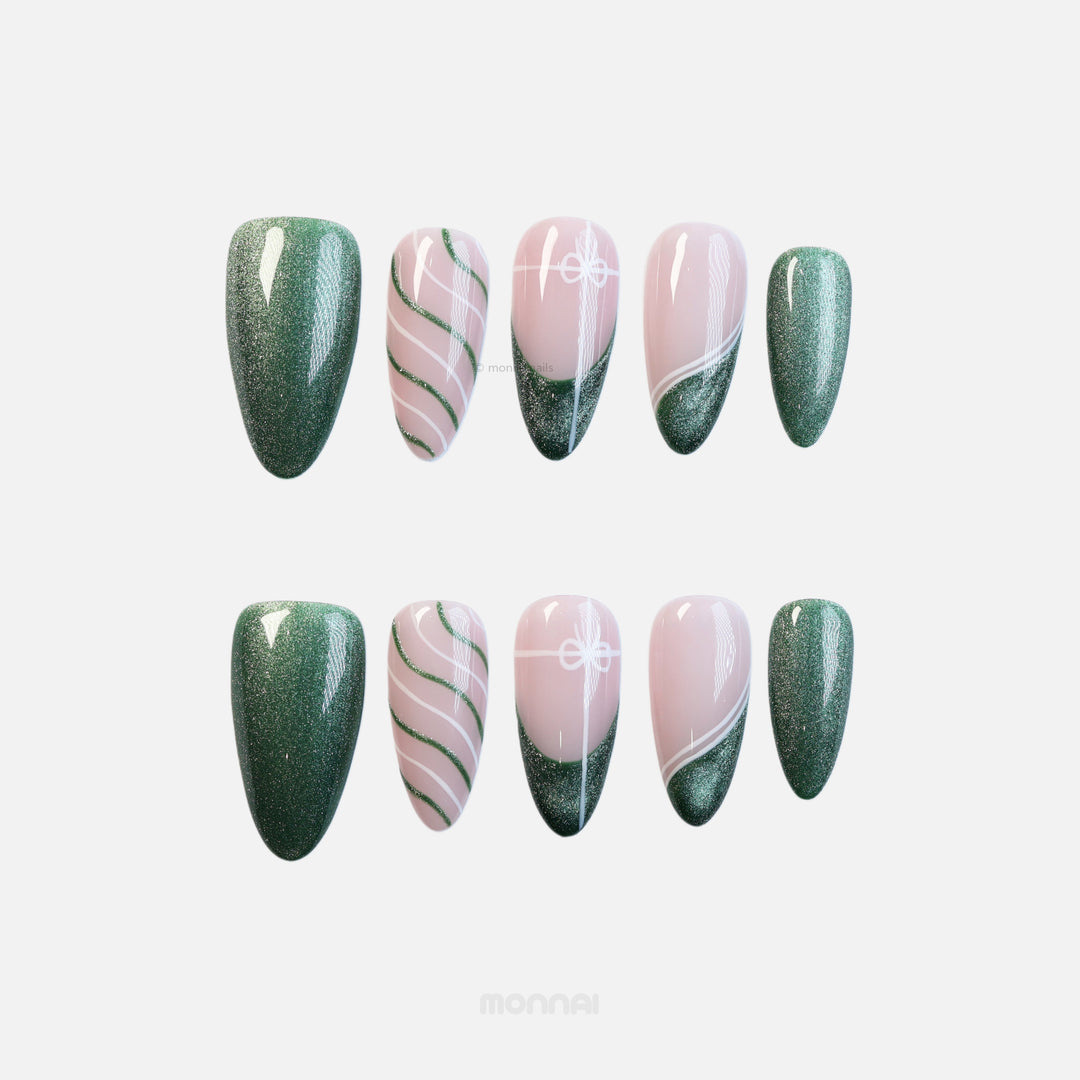 Holiday Cheer press-on nails laid out, with emerald green glitter, soft pink base, and festive ribbon-like white and green line art.