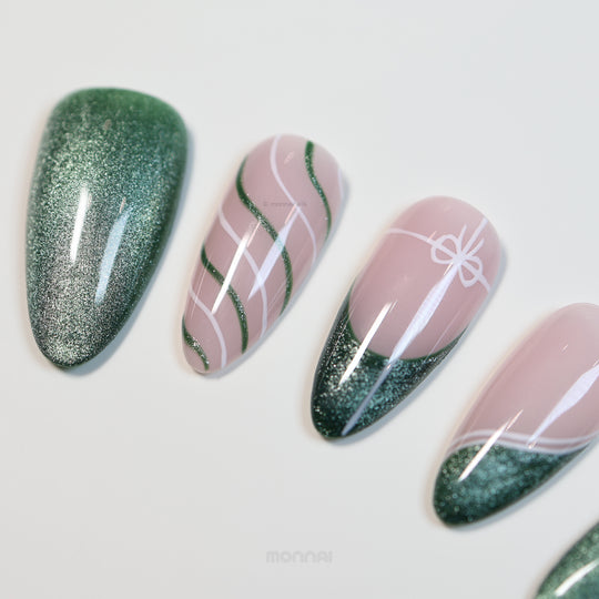 Holiday Cheer press-on nails with emerald cat-eye finish and soft pink ribbon line art, laid out in close-up