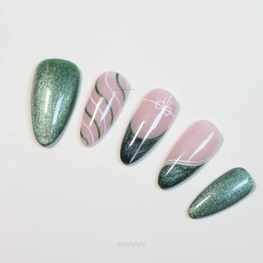 Holiday Cheer press-on nails laid out with emerald green cat-eye and soft pink ribbon line art.