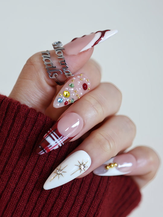 Holiday Glam press-on nails worn on hands with red tartan, jeweled nude nails, white starburst accents, glossy finish