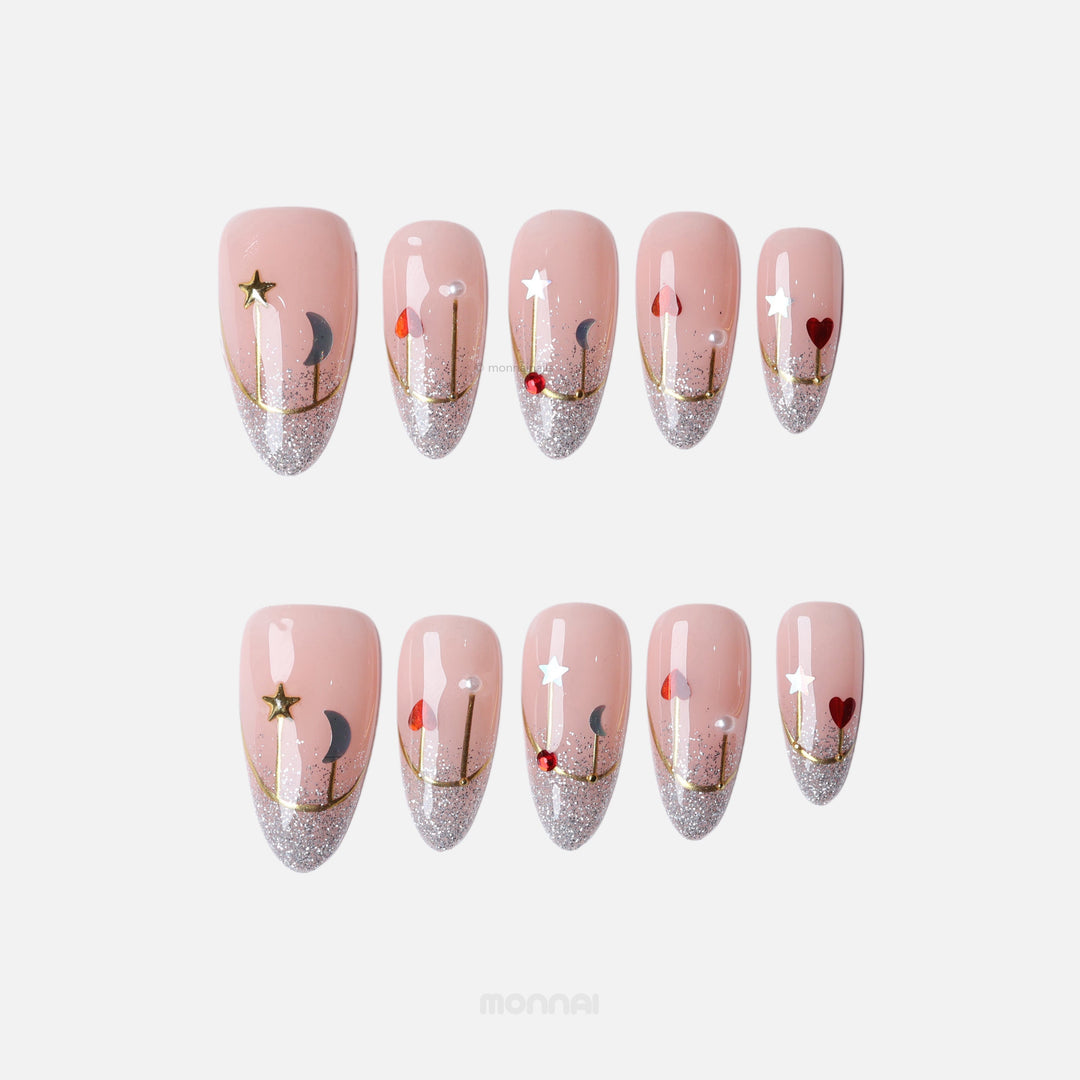 Holiday Glow press-on nails with sheer blush, silver glitter French tips, and gold star, moon, and heart accents