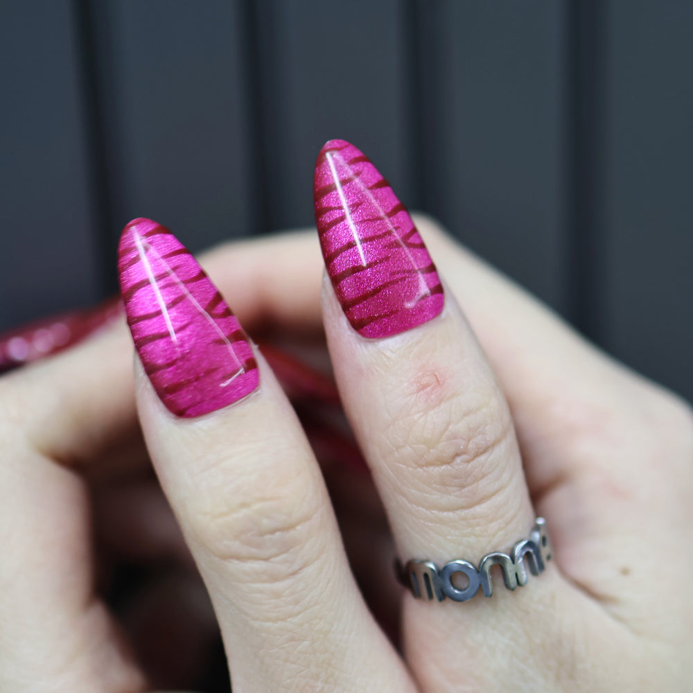 Hot Pink press-on nails on hand with shimmering zebra texture and glossy finish