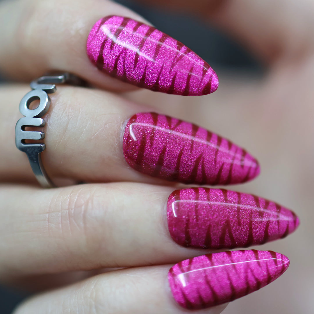 Hot Pink press-on nails on hand with shimmering zebra texture and glossy finish