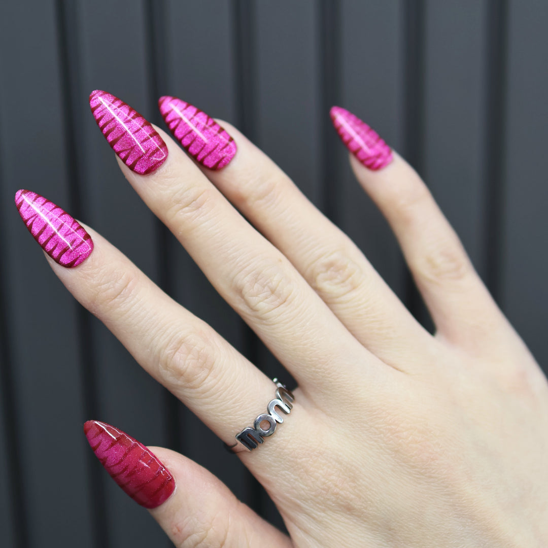 Hot Pink press-on nails on hand with raised zebra texture and glossy finish