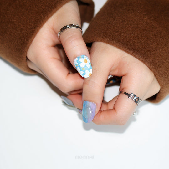 Impressionist Garden press-on nails worn on hand, featuring blue floral brushstrokes and a matte canvas-like finish.
