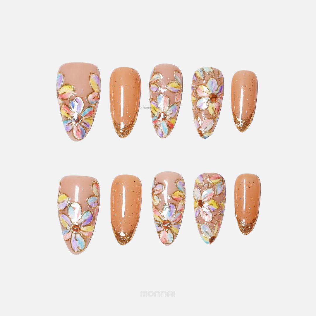 Iridescent Petals press-on nails laid out with pastel floral stained-glass petals and gold French tips