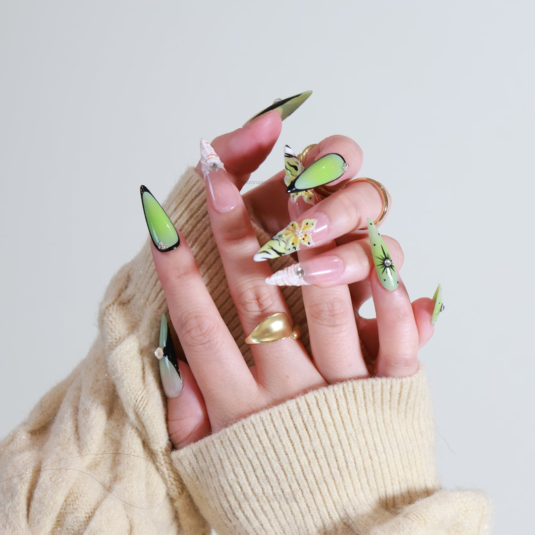 Jade Lotus press-on nails on hand, with matcha green, nude, zebra stripes, floral accents, and crystals in an experimental noir style