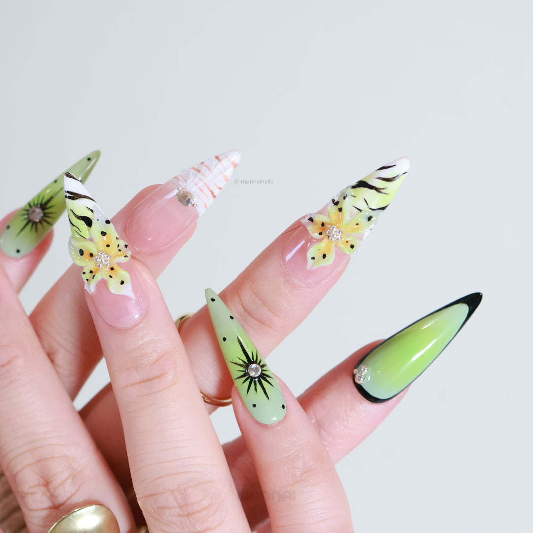 Jade Lotus press-on nails worn on hand, with matcha green and nude zebra stripes, floral accents, crystals, and starbursts.