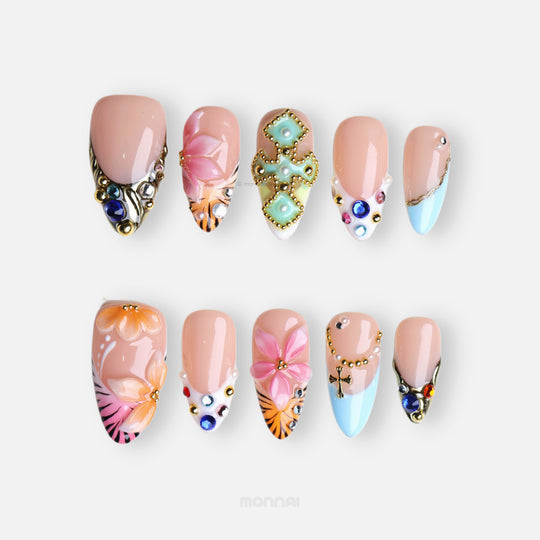 LUX press-on nails set laid out, with summer floral art, sky-blue French tips, gold studs and colorful rhinestones.