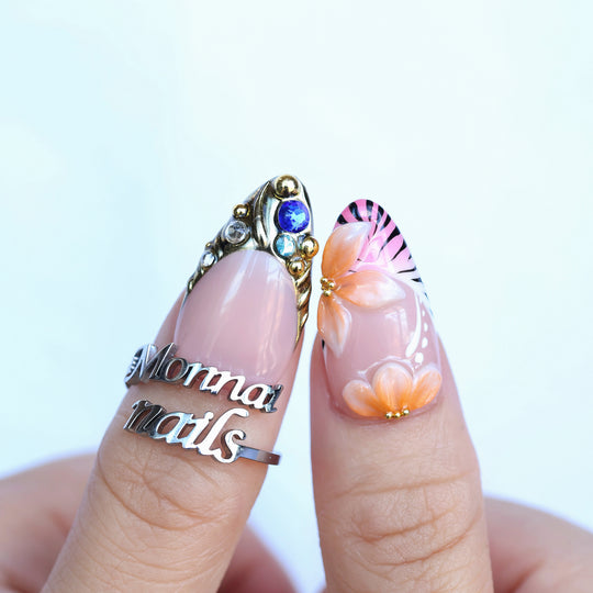 LUX press-on nails with pink floral art, gold studs, and rhinestones shown on fingers in close-up