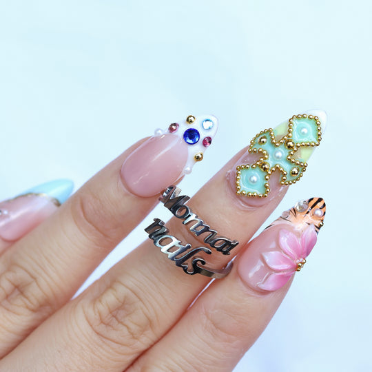 LUX press-on nails worn on hand with sky-blue French tips, floral art, 3D petals, and colorful rhinestones.