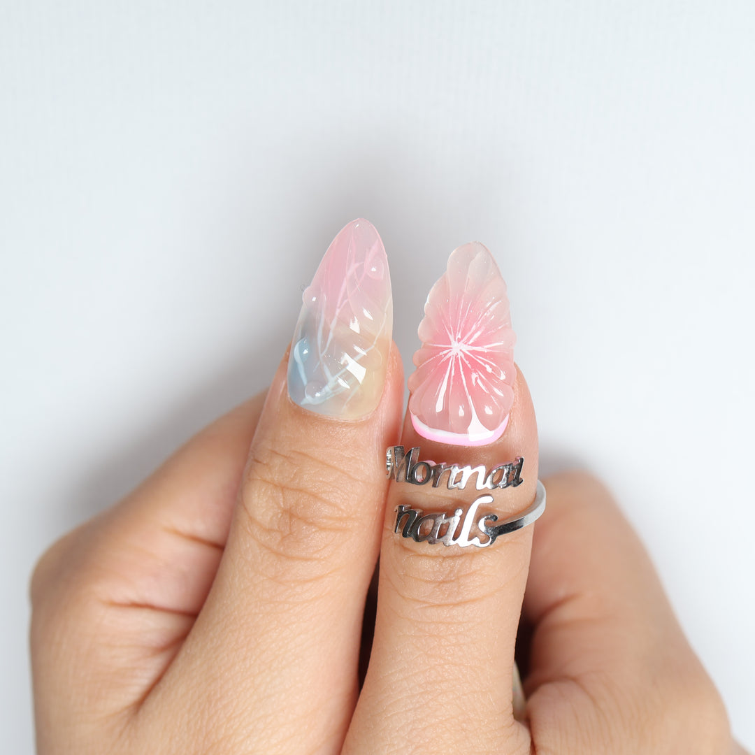 La La Land press-on nails worn on hand, pastel pink and blue with glossy floral accents.