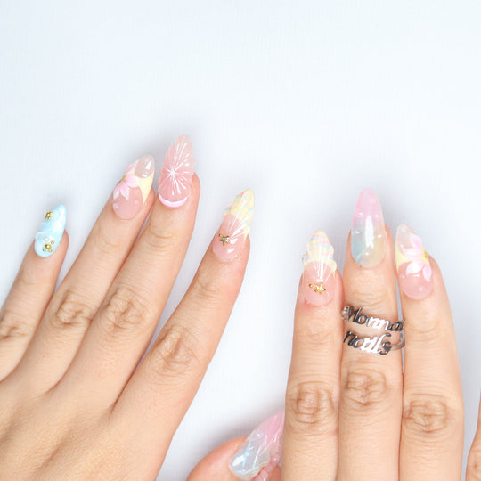 La La Land press-on nails worn on hands, pastel blush pink, sky blue and nude with floral and gold charm details