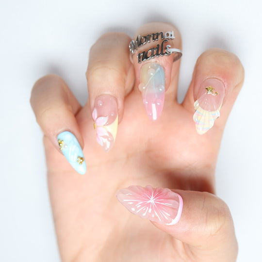 La La Land press-on nails worn on hand, pastel blush pink and sky blue with glossy floral accents and gold charms