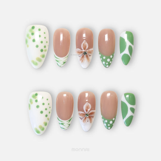 Leaf Dance press-on nails laid out, showing sage green polka dots, wavy French tips, and a 3D flower