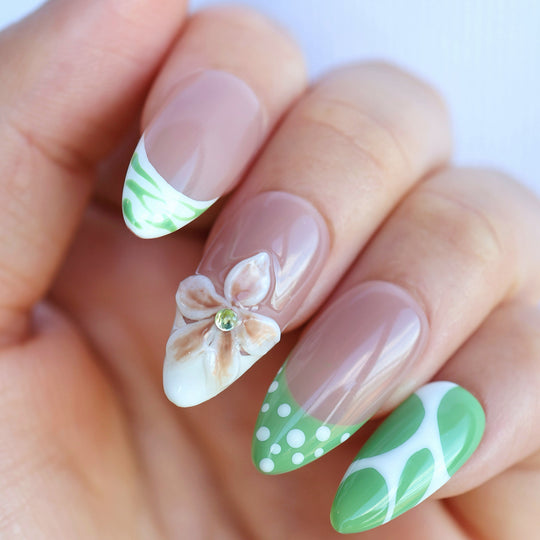 Leaf Dance press-on nails in close-up, with muted sage green polka dots, wavy French tips, and a 3D flower.