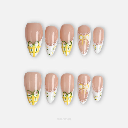 Lemon Lace press-on nails laid out, showing nude bases, white tips, yellow gingham, lace edging, and bows.