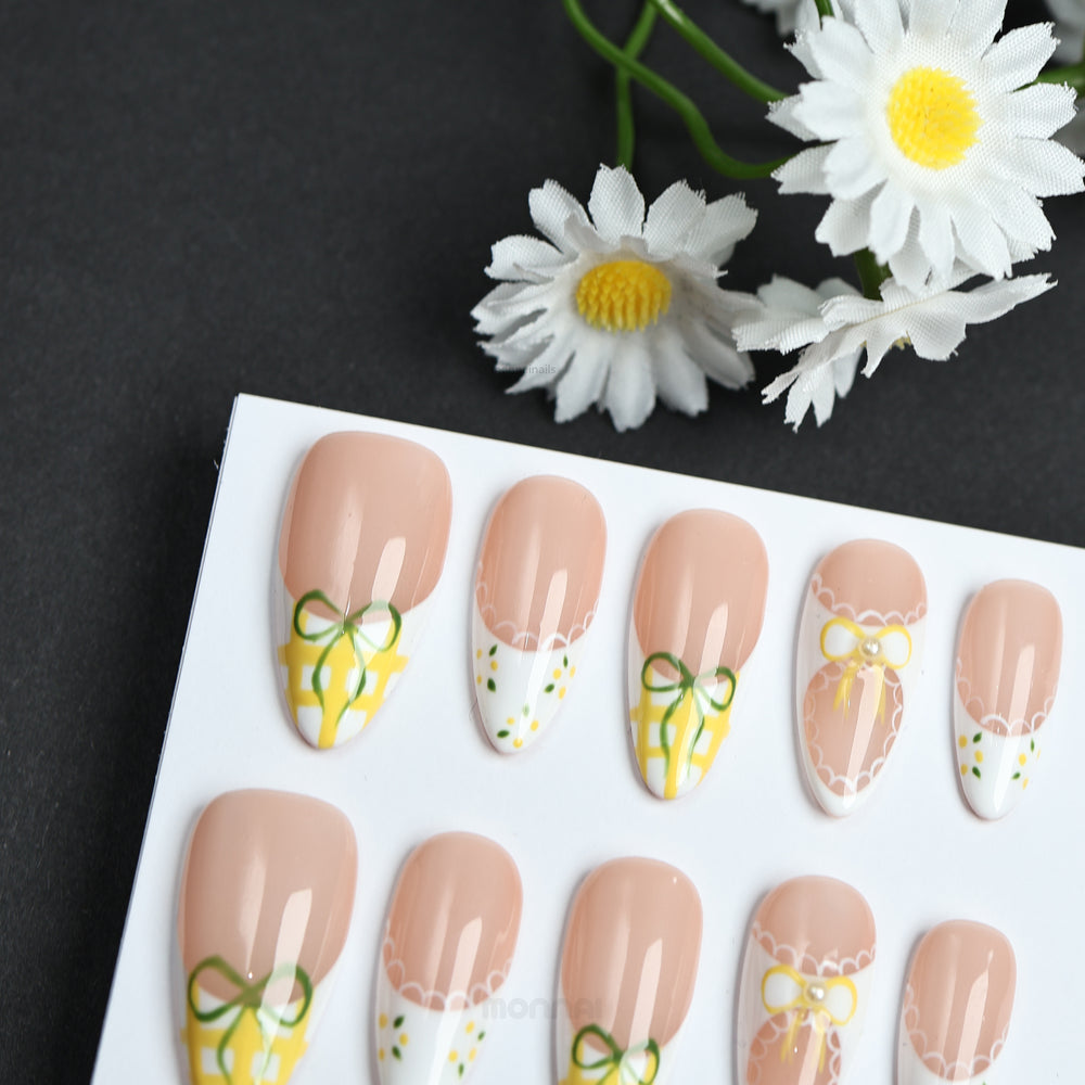 Lemon Lace press-on nails shown on a card, with soft nude bases, white French tips, yellow gingham and bow details