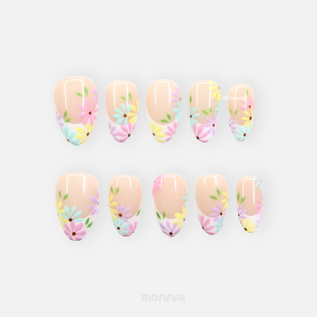 Little Daisy press-on nails laid out with pastel daisy floral tips on nude bases, glossy finish