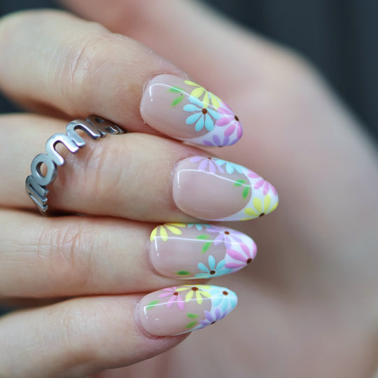 Little Daisy press-on nails on hand, nude base with pastel daisy floral French tips and glossy finish