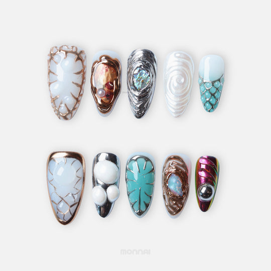 Lost Atlantis press-on nails laid out with ocean blues, chrome frames, pearl accents, and sculpted shell-inspired details.