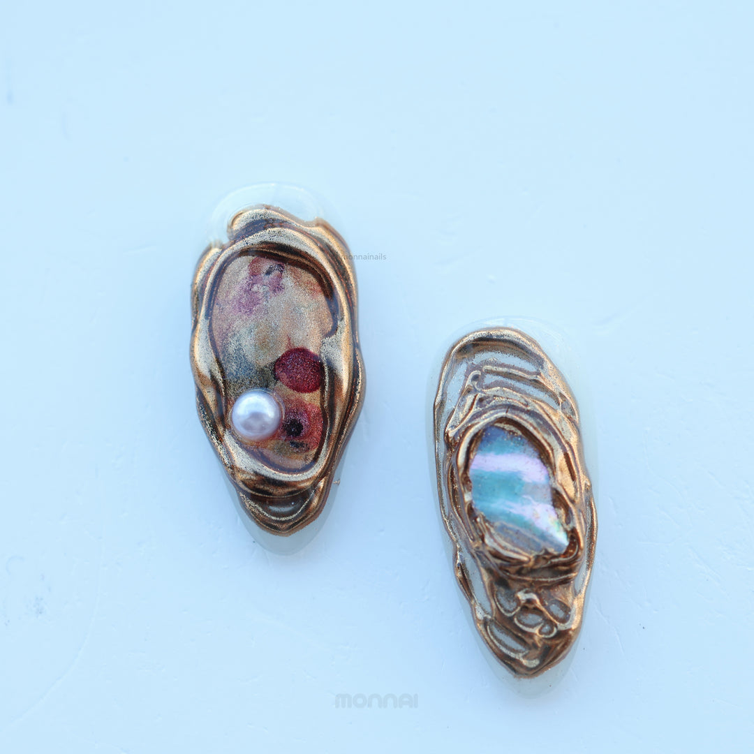 Lost Atlantis press-on nails with sculpted shell shapes, pearl accent and chrome marbled sheen, shown close-up.
