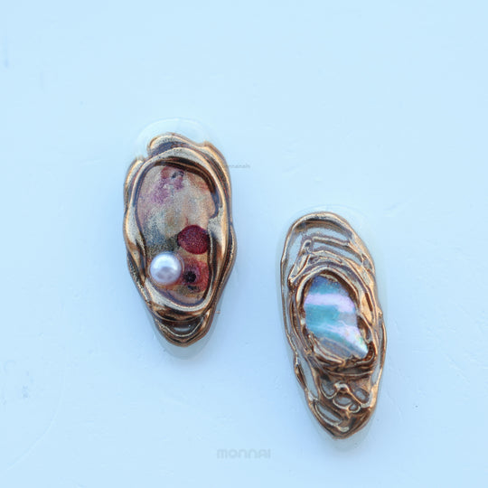 Lost Atlantis press-on nails with sculpted shell shapes, pearl accent and chrome marbled sheen, shown close-up.