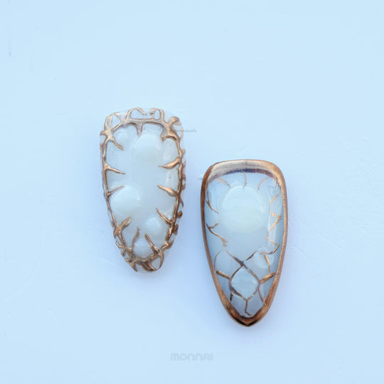 Lost Atlantis press-on nails laid out, showing sculpted shell shapes, fluid chrome frames, and pearl accents.
