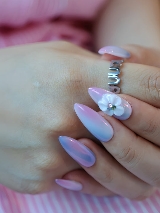 Lost in Petalight press-on nails worn on hand, dreamy pink and lavender chrome with a sculpted floral accent