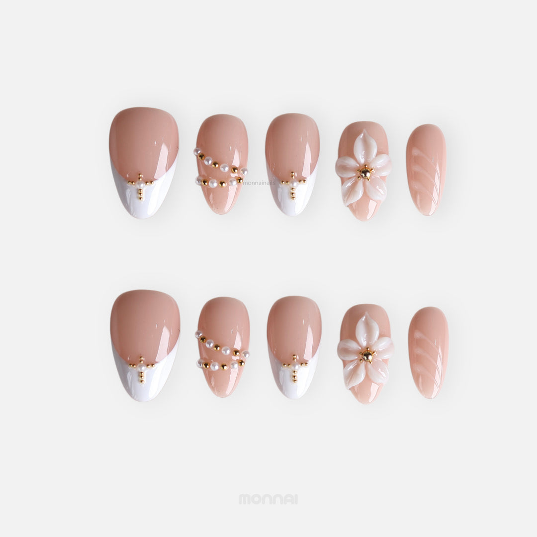 Love Story press-on nails in soft nude and white French tips with pearl and gold bead accents, 3D floral detail