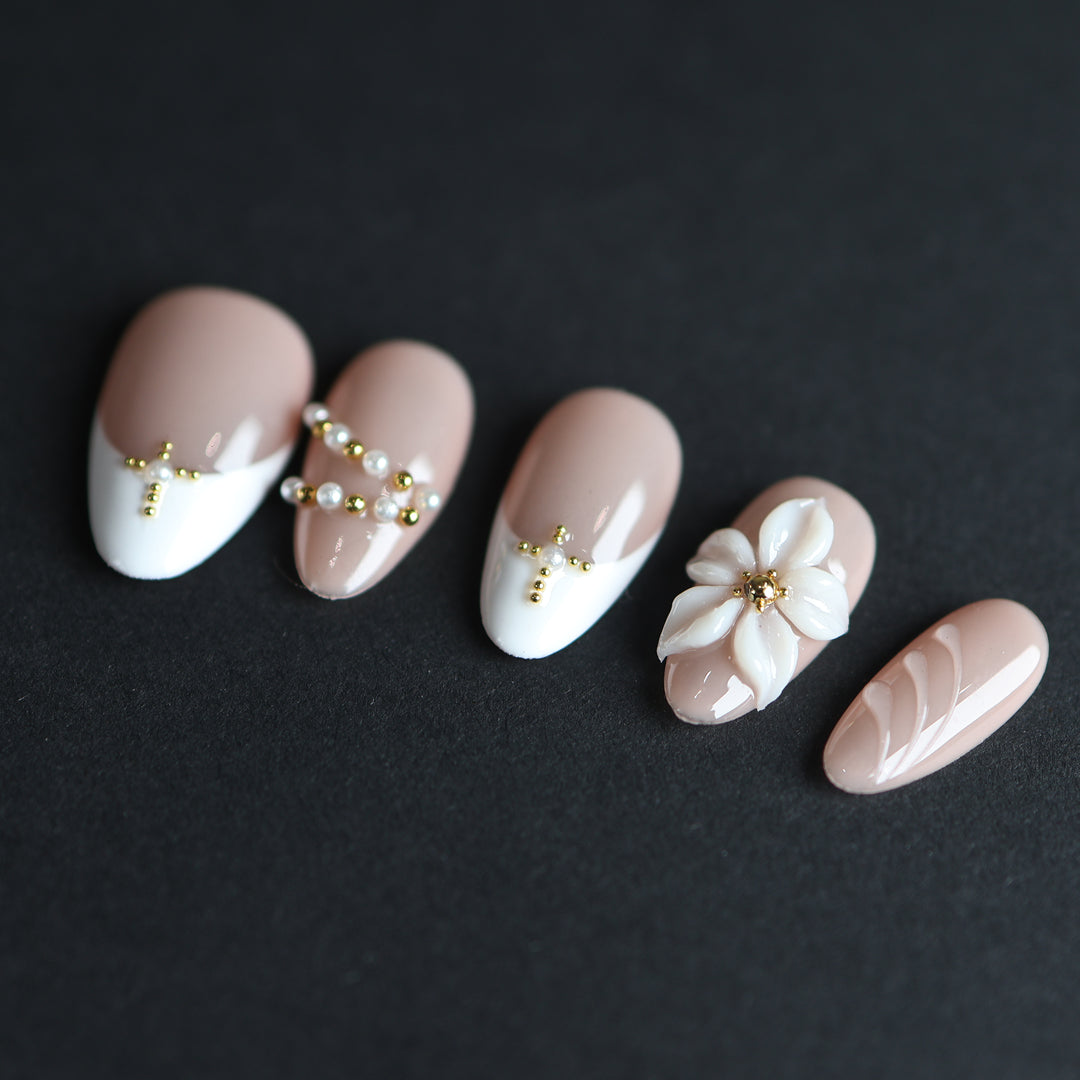 Love Story press-on nails laid out with white French tips, 3D floral detail, and pearl-and-gold-bead accents