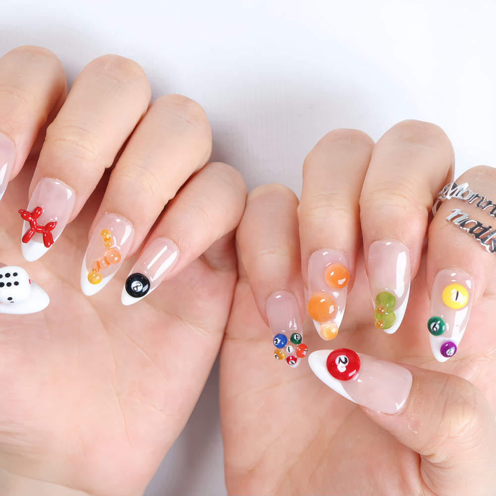 Lucky Numbers press-on nails worn on hands with sheer nude French tips, colorful billiard balls, dice, and glossy Y2K game-inspired details.