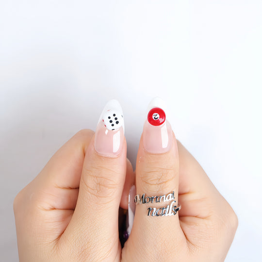 Lucky Numbers press-on nails shown on hands with sheer nude and white French tips, featuring dice and billiard ball accents.