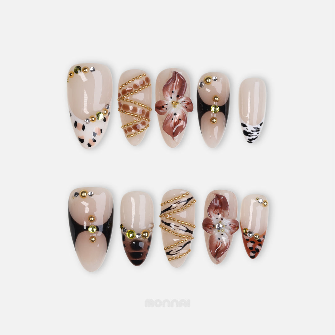 Madam Cheetah press-on nails with nude base, leopard and zebra accents, floral details, and gold rhinestones, laid out in close-up.