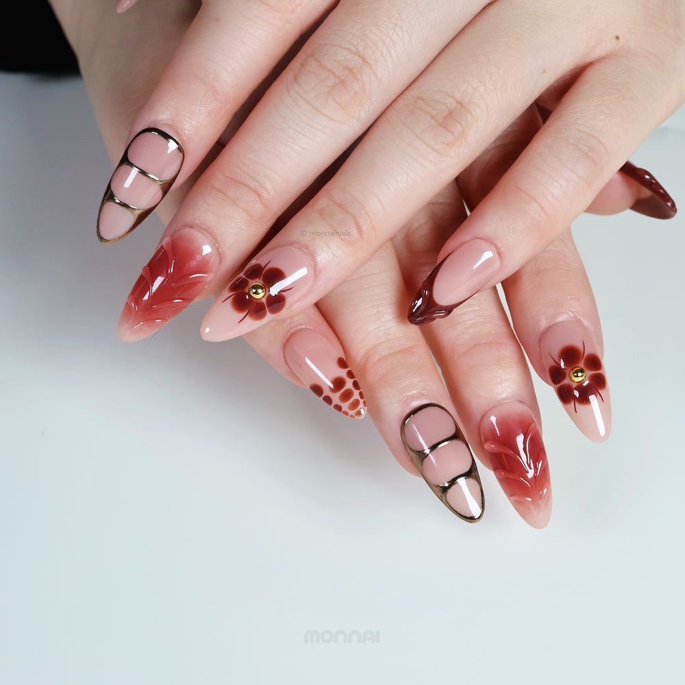 Maple Glow press-on nails worn on hands with nude bases, rich brown accents, floral details, and glossy vintage-inspired contrast.