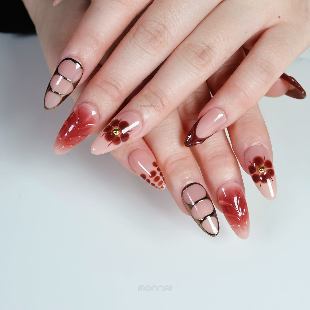 Maple Glow press-on nails worn on hands with nude bases, rich brown accents, floral details, and glossy vintage-inspired contrast.