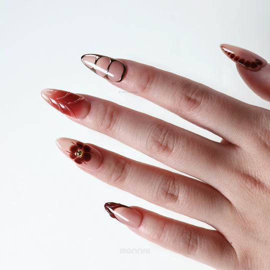 Maple Glow press-on nails worn on hand with nude base, rich brown accents, floral details, and glossy vintage-style finish