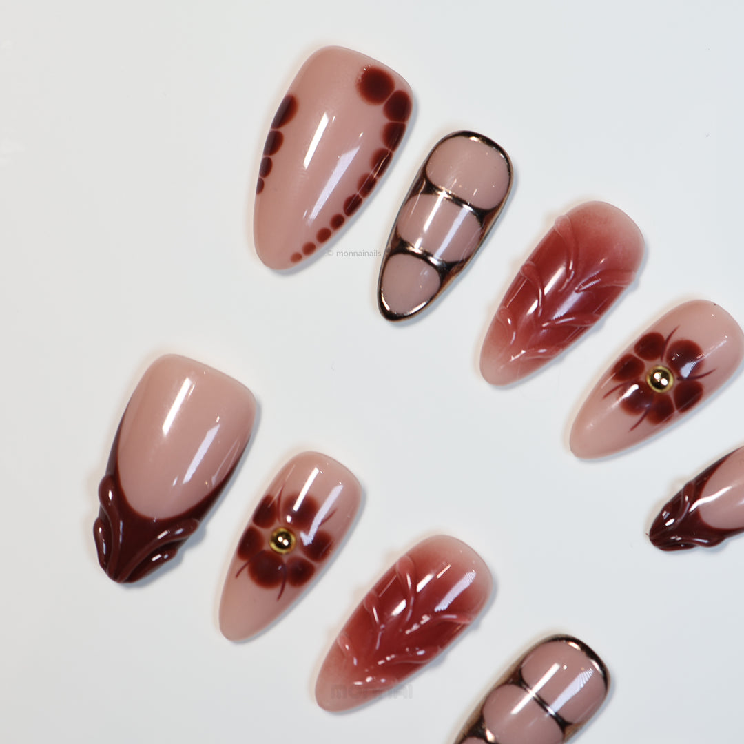 Maple Glow press-on nails laid out in warm brown and nude vintage floral designs with glossy accents