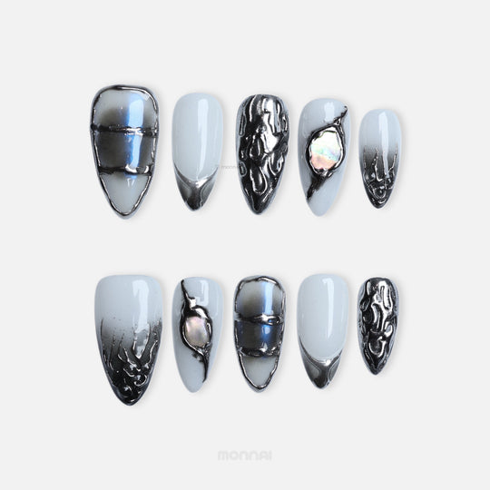 Metal Blaze press-on nails laid out in cool grey with chrome edging and iridescent inlay, plus sculpted accents.