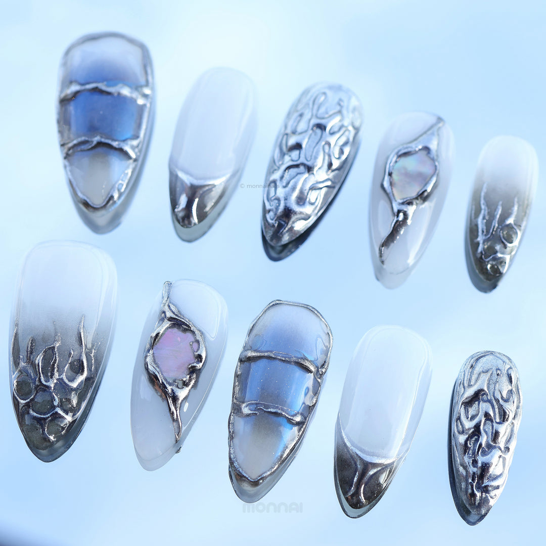 Metal Blaze press-on nails laid out in a cool modern design with grey tones, chrome edges, sculpted accents, and iridescent inlays